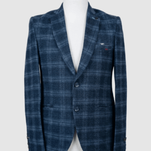 A men's tailored smart fit coat in a deep blue plaid and textured fabric on a mannequin. The coat features a lapel pin, dark buttons, and a unique silver metallic pocket accent. Turkish stitching and branded fabric are present.