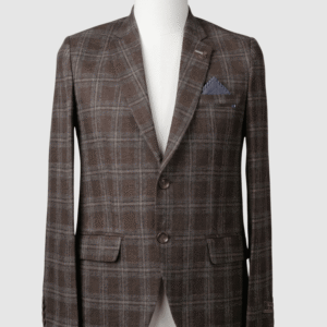 A tailored smart fit coat in a brown check pattern on a mannequin. The coat features a subtle lapel pin, brown buttons, and a contrasting blue patterned pocket square. Turkish stitching and branded fabric are present.