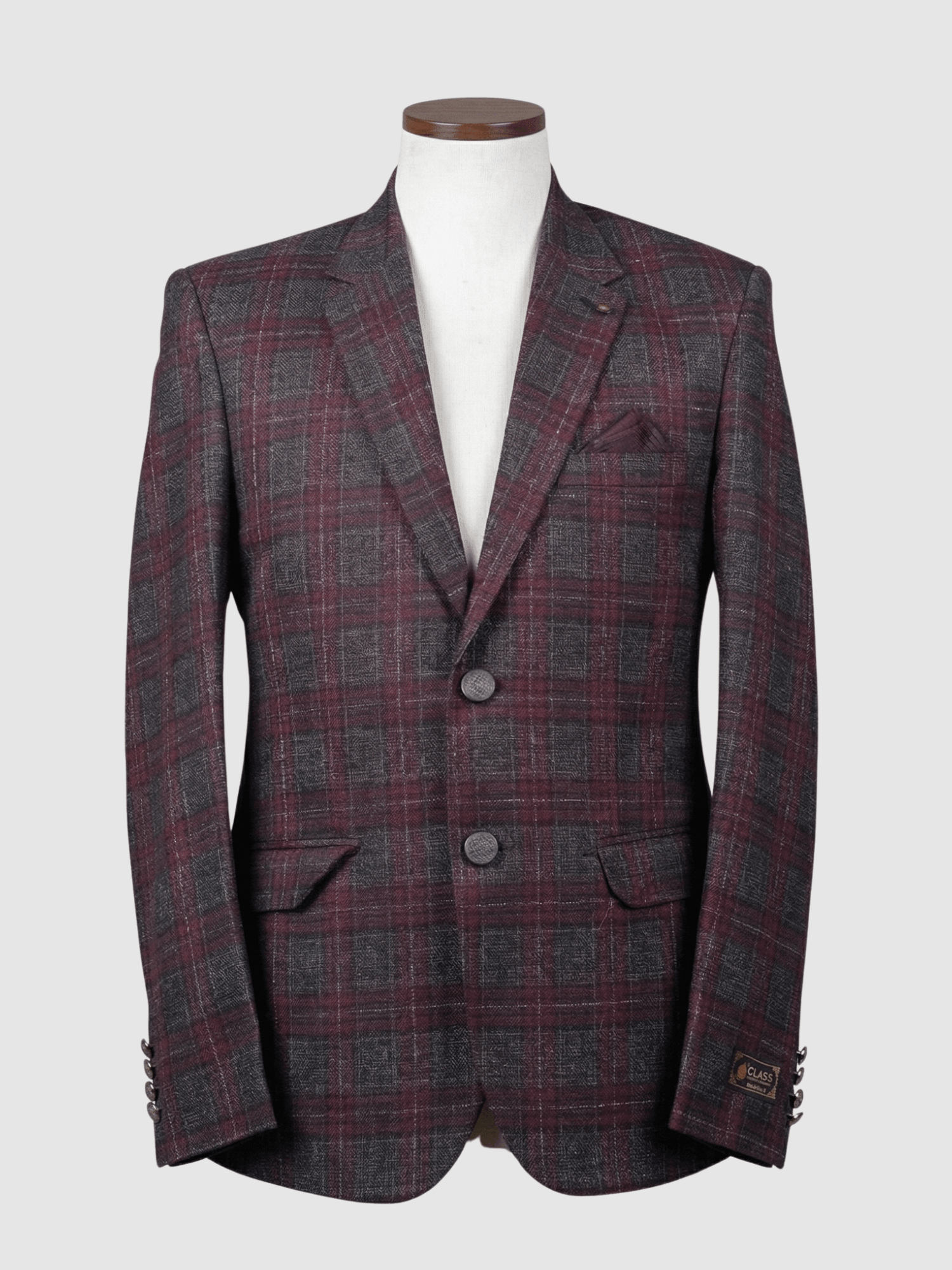 Iranian Fabric Burgundy Plaid Smart Fit Coat - Kamal Clan A tailored smart fit coat made of Iranian burgundy and charcoal grey plaid fabric on a mannequin. The coat features a subtle lapel pin, textured dark buttons, and a matching dark pocket square.
