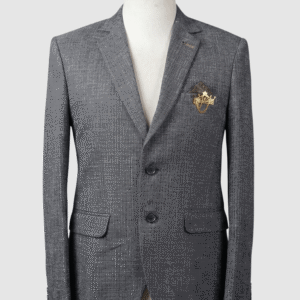 A tailored smart fit coat made of textured grey Iranian fabric on a mannequin. The coat features a lapel pin, dark buttons, a dark pocket square, and a prominent gold crown brooch with hanging chains.